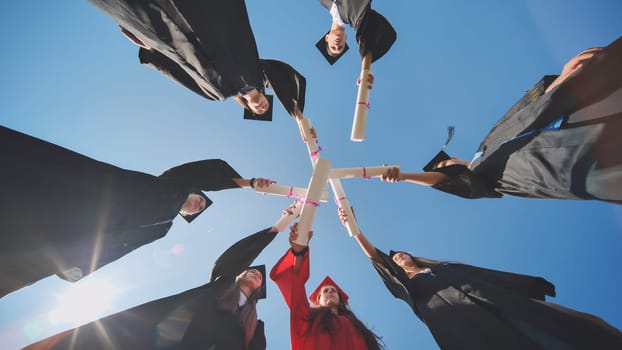 College graduates join hands with their diplomas. The concept of friendship