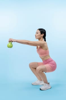 Vigorous energetic woman doing kettlebell weight lifting exercise on isolated background. Young athletic asian woman strength and endurance training session as body workout routine.