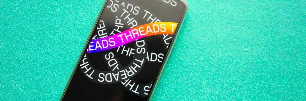 Tver, Russia - July 15, 2023, threads logo on the smartphone screen, on a green background. The threads icon. The logo of the current application. Threads social network