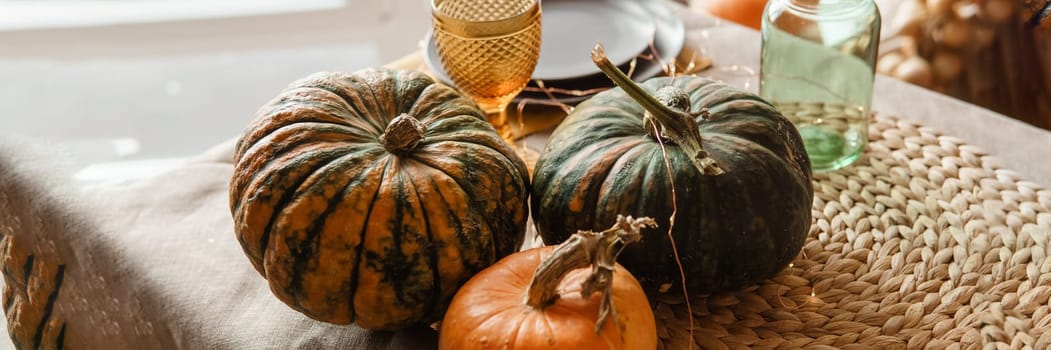 Autumn interior: a table covered with dishes, pumpkins, a relaxed composition of Japanese pampas grass. Interior in the photo Studio. Close - up of a decorated autumn table