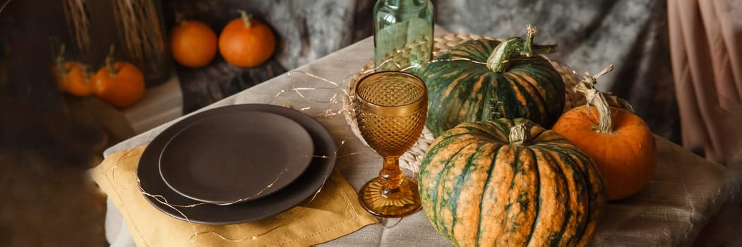 Autumn interior: a table covered with dishes, pumpkins, a relaxed composition of Japanese pampas grass. Interior in the photo Studio. Close - up of a decorated autumn table