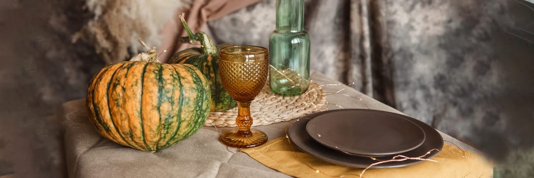 Autumn interior: a table covered with dishes, pumpkins, a relaxed composition of Japanese pampas grass. Interior in the photo Studio. Close - up of a decorated autumn table