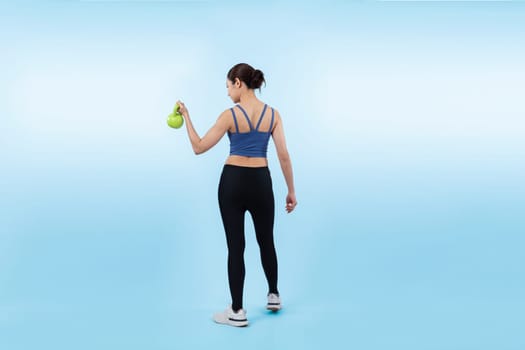 Vigorous energetic woman doing kettlebell weight lifting exercise on isolated background. Young athletic asian woman strength and endurance training session as body workout routine.