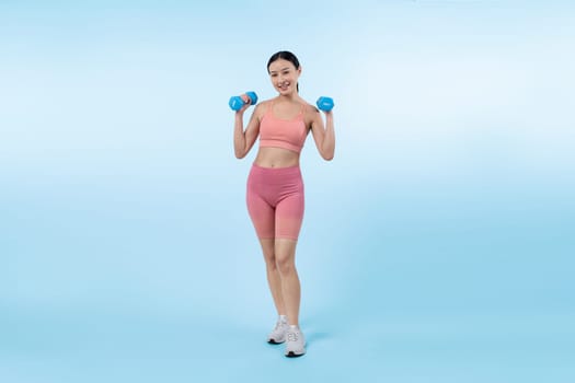 Vigorous energetic woman doing dumbbell weight lifting exercise on isolated background. Young athletic asian woman strength and endurance training session as body workout routine.