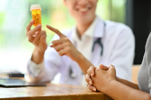 Doctor holding pills bottles explaining instructions of medicine to patient. Medicine and health care service concept.