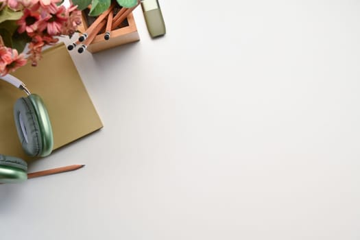 A wireless headphone, notebook and pencil holder on white table. Top view with copy space for text.