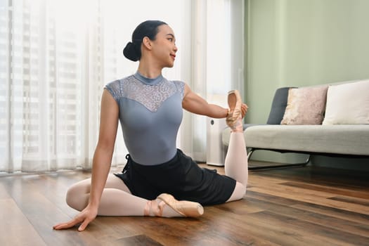 Beautiful young ballerina practicing in the flexibility of home. Dance art, education and choreography.