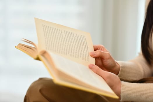 Young woman reading book, enjoying leisure weekend time at home. Education, leisure and lifestyle concept.