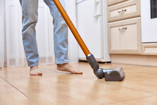 close-up, woman uses cordless vacuum cleaner to clean floor.