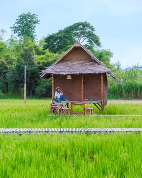 Asian Thai woman on vacation at a small homestay at the farm with a green rice paddy field in Central Thailand