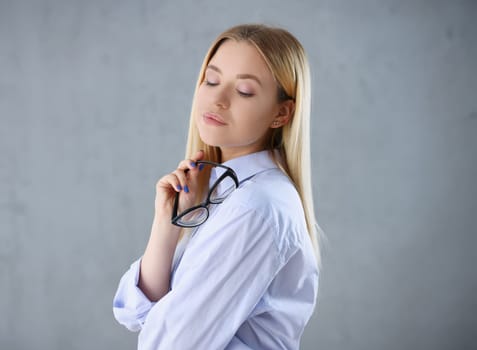 Portrait of a sexy woman in a man's shirt wearing glasses on a gray background looks at the camera. Smiling look advice to give wants objections are not accepted.