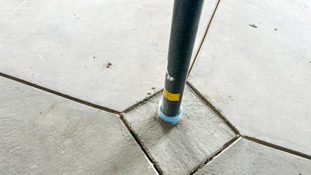 Castle Pines, Colorado USA - January 18, 2023-Close-up of a metal structural support post anchored into a concrete basement floor in a new single-family home under construction. The post is securely positioned at the intersection of neatly cut concrete sections, highlighting construction precision.