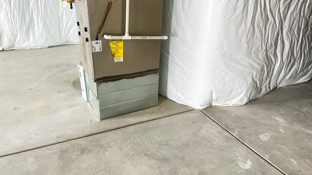 Castle Pines, Colorado USA - January 18, 2023-Furnace unit installed in an unfinished basement of a new single-family home under construction. The basement features concrete flooring and white insulation on the walls, highlighting the structural and utility setup in progress.