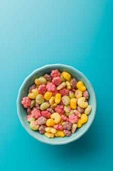 Colorful breakfast cereals in the shape of various fruit in bowl on a blue background. Top view.