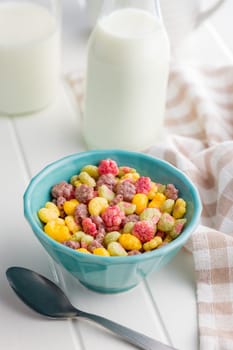 Colorful breakfast cereals in the shape of various fruit in bowl on a white table.