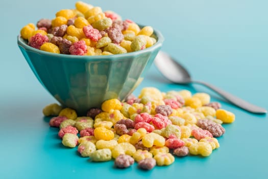 Colorful breakfast cereals in the shape of various fruit in bowl on a blue background.
