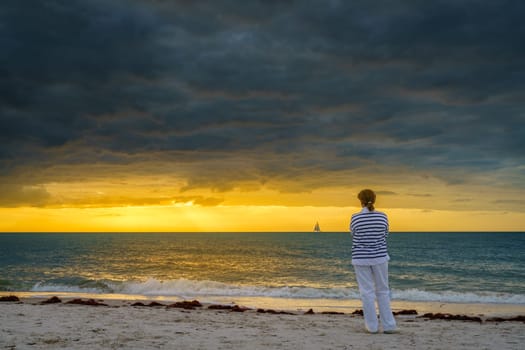 A woman is watching sunset on the beach in Naples, Florida