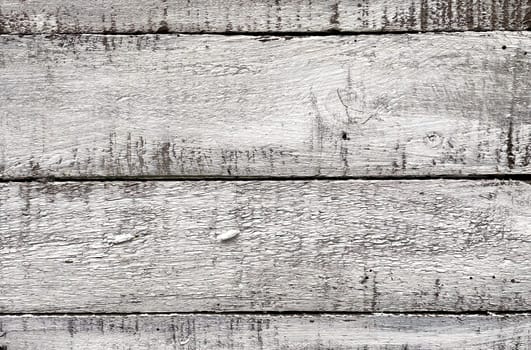 A close-up view of weathered white wooden planks. The texture of the wood is prominently displayed, showcasing the natural grain, knots, and imperfections that give it a rustic and aged appearance. The white paint is worn and chipped in places, adding to the vintage and distressed look. This background is ideal for use in design projects that require a natural, rustic, or shabby chic aesthetic.