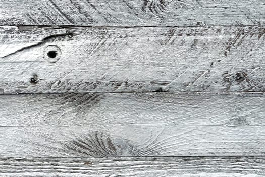 A close-up view of weathered white wooden planks. The texture of the wood is prominently displayed, showcasing the natural grain, knots, and imperfections that give it a rustic and aged appearance. The white paint is worn and chipped in places, adding to the vintage and distressed look. This background is ideal for use in design projects that require a natural, rustic, or shabby chic aesthetic.