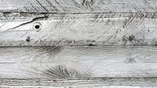 A close-up view of weathered white wooden planks. The texture of the wood is prominently displayed, showcasing the natural grain, knots, and imperfections that give it a rustic and aged appearance. The white paint is worn and chipped in places, adding to the vintage and distressed look. This background is ideal for use in design projects that require a natural, rustic, or shabby chic aesthetic.