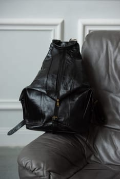 Black leather backpack on chair, close up..