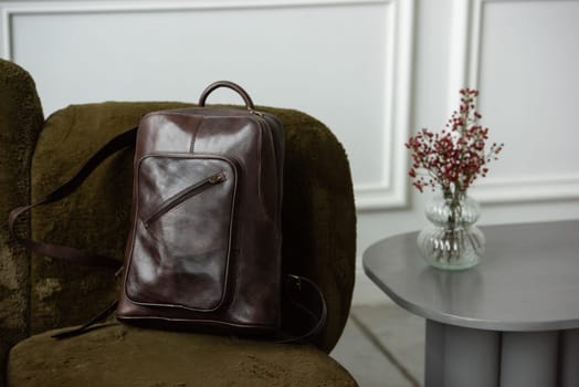 Brown leather backpack on chair, close up.