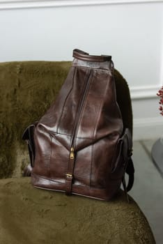 Brown leather backpack on sofa, close up.