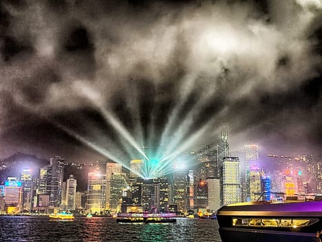 Hong Kong - April 05, 2024: Vibrant lights illuminate the night sky over Victoria Bay as the skyline of Hong Kong sparkles. The evening light show captivates viewers with its colorful display and urban beauty.
