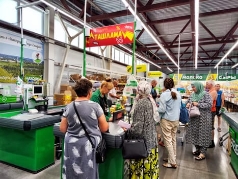 Yelabuga, Russia - July 21, 2024: Customers engage with the cashier at a busy grocery store in Yelabuga, Russia, creating a vibrant shopping atmosphere.