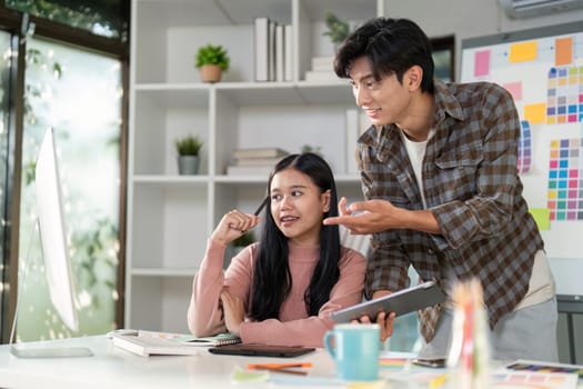 Creative designers discussing graphics and artistic ideas at a stylish workspace, one presenting concepts on a tablet while the other listens intently with enthusiasm.