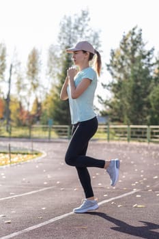 A young beautiful woman in sportswear plays sports at a local stadium. Exercise, jog and exercise at the beginning of the day. Healthy and active lifestyle.