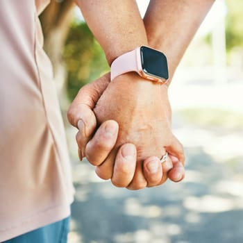 Closeup, holding hands and support with trust for love in bond, together or romance while walking. Elderly couple, man and woman in retirement with exercise for wellness, health or smart watch.