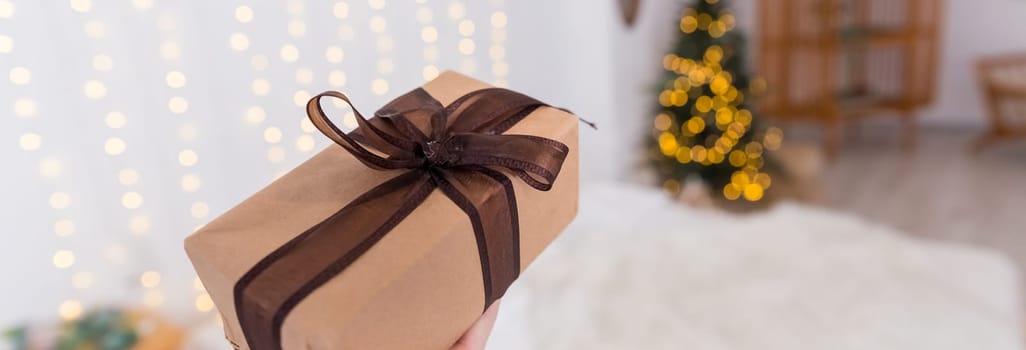 Wrapped Christmas presents on cozy bed next to Christmas tree with beautiful blurred lights on the background.