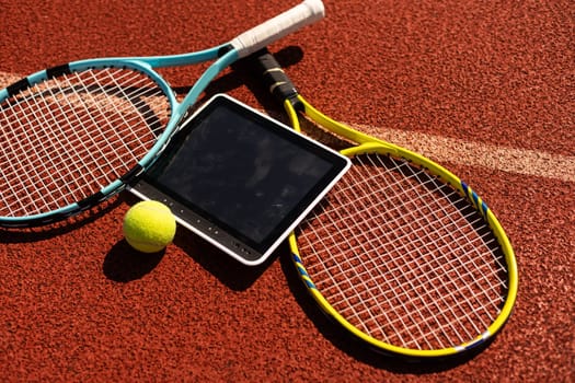 High angle view of tennis racket and ball by digital tablet on maroon background. High quality photo