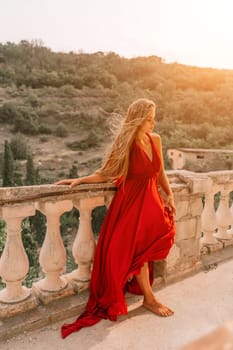 Woman red dress. Summer lifestyle of a happy woman posing near a fence with balusters over the sea