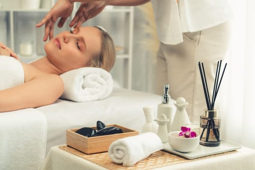 Caucasian woman enjoying relaxing anti-stress head massage and pampering facial beauty skin recreation leisure in dayspa modern light ambient at luxury resort or hotel spa salon. Quiescent