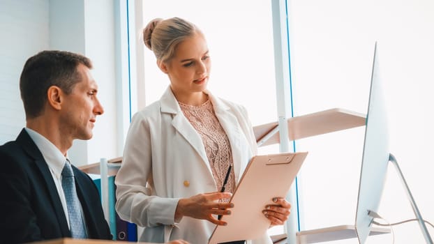 Two business people talk project strategy at office meeting room. Businessman discuss project planning with colleague at modern workplace while having conversation and advice on financial report. Jivy