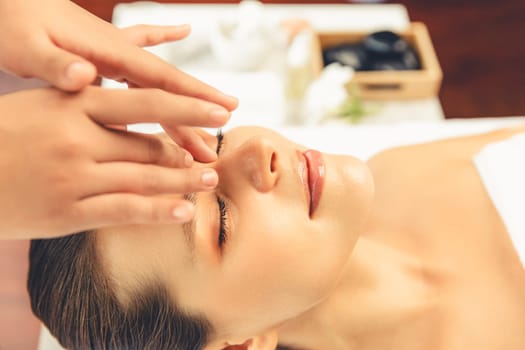 Closeup woman enjoying relaxing anti-stress head massage and pampering facial beauty skin recreation leisure in dayspa modern light ambient at luxury resort or hotel spa salon. Quiescent