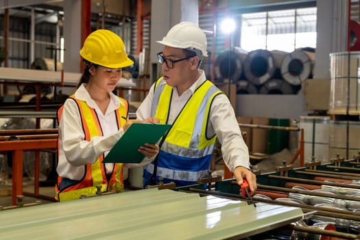 Factory engineer manager collaborate with coworker to conduct quality control on metal sheet product and inspect heavy industrial steel stamping or forming machine. Exemplifying