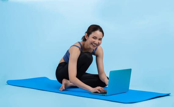 Young asian woman in sportswear stretching before fitness exercise following instruction from online video. Body workout with healthy athletic woman warming up on isolated background. Vigorous