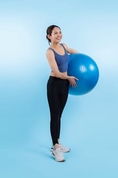 Young attractive asian woman portrait in sportswear with fit ball targeting on abs muscle for effective energetic daily workout routine. Studio shot and isolated background. Vigorous