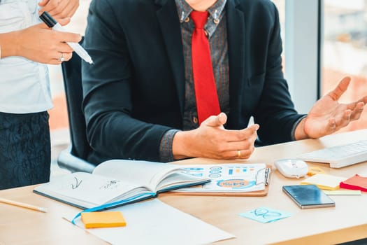 Two business people talk project strategy at office meeting room. Businessman discuss project planning with colleague at modern workplace while having conversation and advice on financial report. Jivy