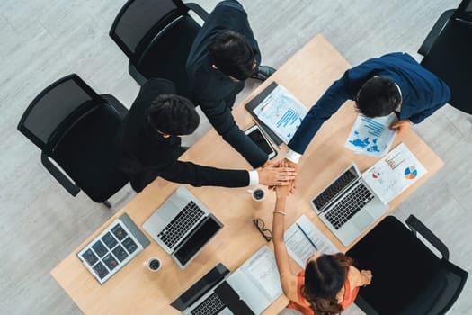 Happy business people celebrate teamwork success together with joy at office table shot from top view . Young businessman and businesswoman workers express cheerful victory show unity support . Jivy