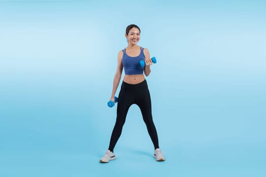 Vigorous energetic woman doing dumbbell weight lifting exercise on isolated background. Young athletic asian woman strength and endurance training session as body workout routine.