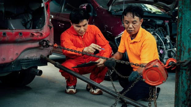 Mechanic testing strength and reliability of chain hoist for car towing in car workshop garage. Automotive service worker ensure through inspection of mechanical equipment. Oxus