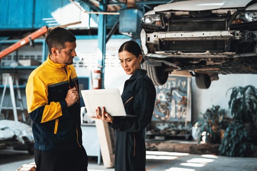 Two vehicle mechanic working together, conduct car inspection with laptop. Automotive service technician in uniform carefully make diagnostic troubleshooting to identify error. oxus