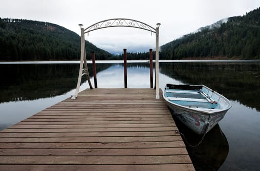 A small rowboat is anchored to a dock on the calm Mirror Lake near Sagle, Idaho.