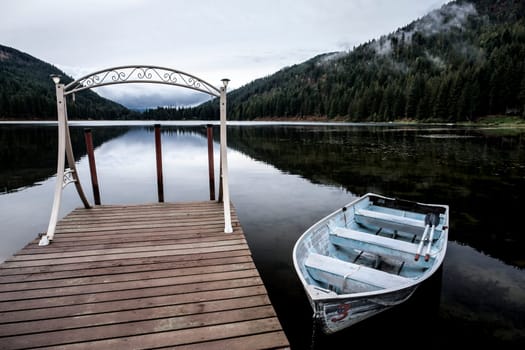 A small rowboat is anchored to a dock on the calm Mirror Lake near Sagle, Idaho.