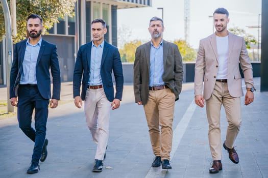 Four businessmen in smart and formal attire walking outdoors in an urban setting, exuding confidence, teamwork, and professionalism.