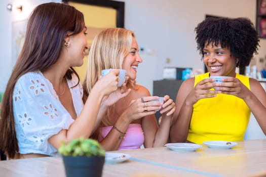 A group of three diverse women sitting at a table, holding coffee cups and laughing together in a cozy cafe. Warm and cheerful atmosphere, symbolizing friendship and connection.
